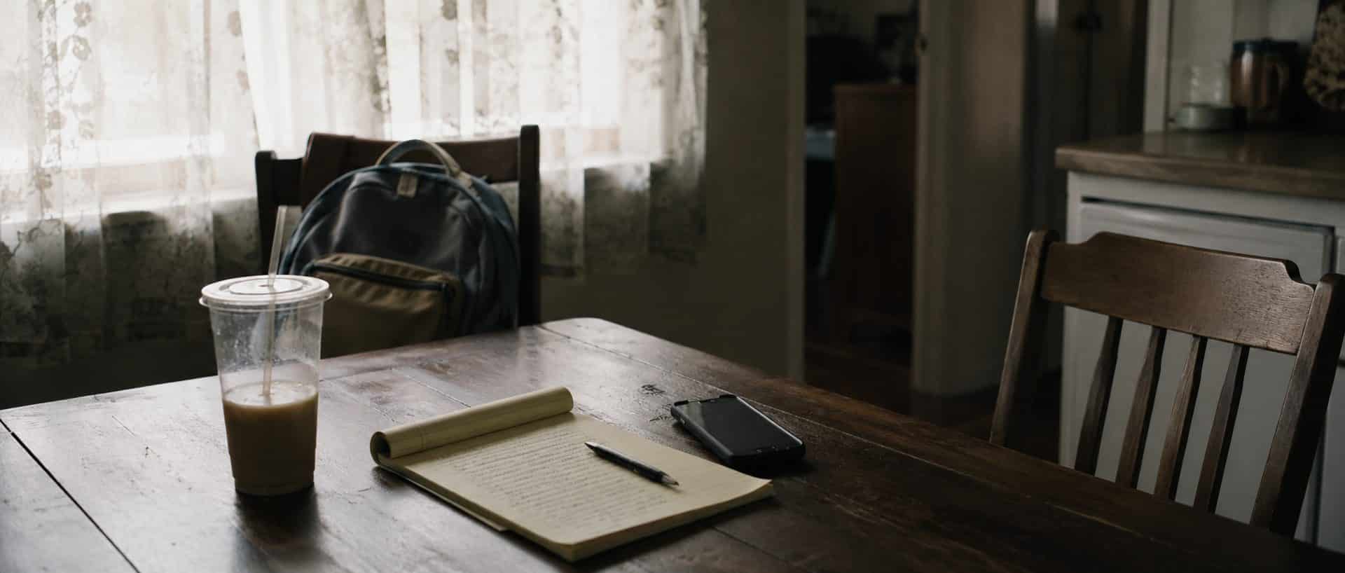 A kitchen table in an East Texas home with a legal pad, phone and a school backpack, and one chair empty.