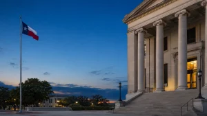 Texas county courthouse columns and a Texas flag at blue hour